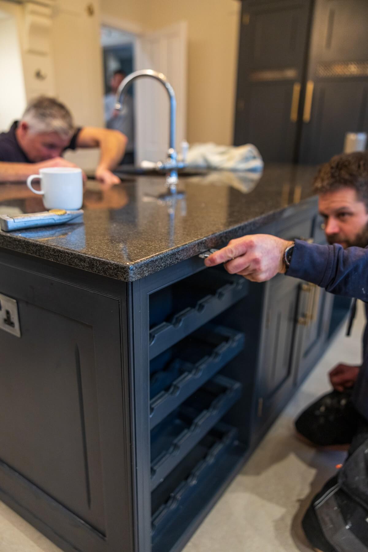 Surrey Marble and Granite experts installing black granite surfaces into a kitchen.